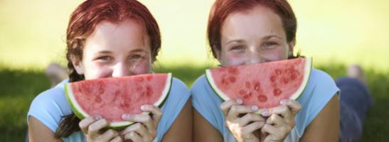 Foto di due giovani donne con delle fette di anguria sul viso. Questa immagine mostra come seguire questi consigli sullo stare bene vi aiuterà a fare le cose che preferite durante il ciclo.