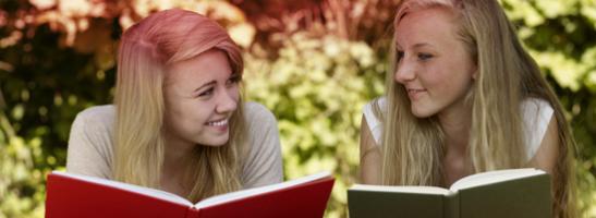 Immagine di due giovani donne che leggono un libro. La foto mostra i molti miti associati alle mestruazioni.